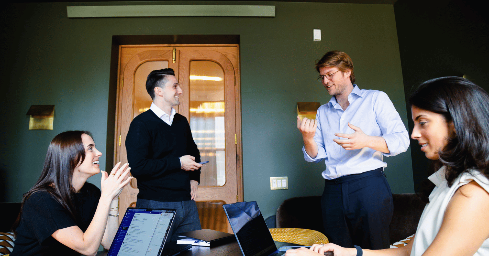 Fredriks Executive Search colleagues in conversation, two people standing and two sitting in the foreground.