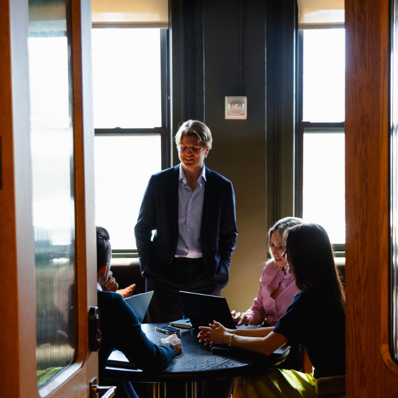 Photo shot through a door of four Fredriks Executive Search colleagues in conversation. Contact Us.
